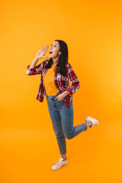 Photo of beautiful young woman posing and screaming isolated over yellow background - Foto, afbeelding