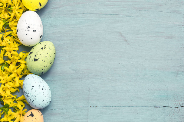 Fondo de Pascua. Huevos y flores sobre mesa de madera azul. Copiar espacio
 - Foto, imagen