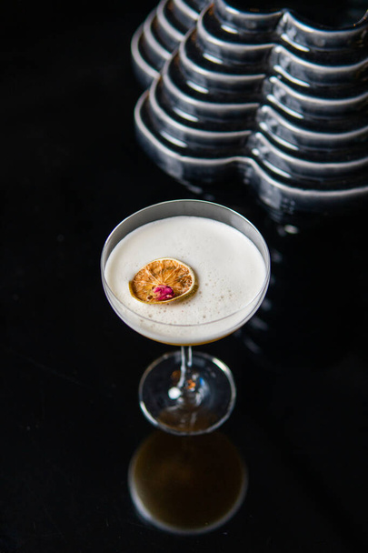 vista ravvicinata di vetro di cocktail bianco con fetta di agrumi riflessa su sfondo nero
  - Foto, immagini