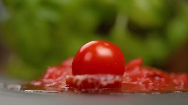 Ripe ronde tomaat valt in een plas marinara saus op de tafel. - Video