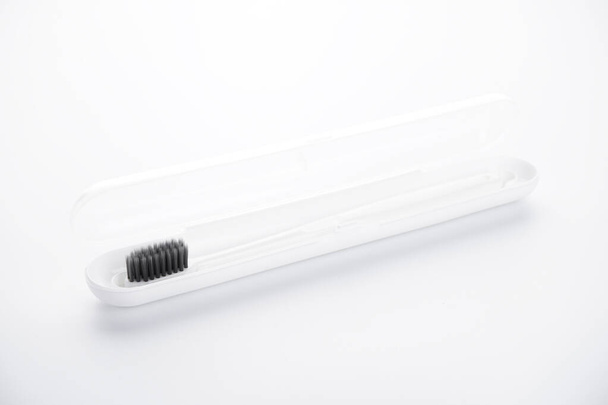 Cepillo de dientes blanco con escudo negro en una caja blanca sobre un fondo blanco. Aislado
. - Foto, Imagen