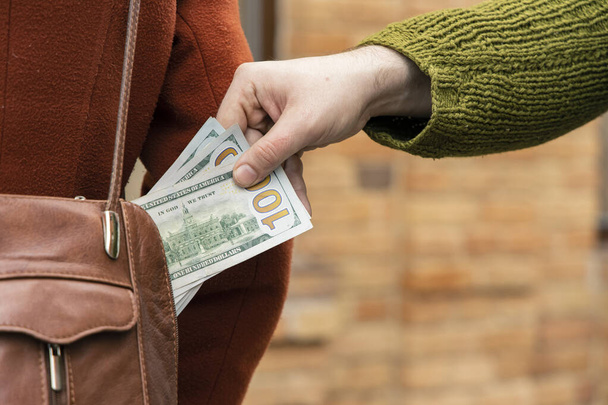 κλέβουν χρήματα από τσάντα γυναίκα ύφασμα μόδας και ανδρικό χέρι με δολάρια έννοια μετρητά εικόνα δρόμο - Φωτογραφία, εικόνα