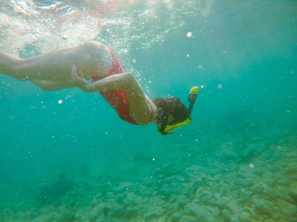 nő piros fürdőruhában víz alatt búvármaszk és uszony nyári vakáció - Fotó, kép