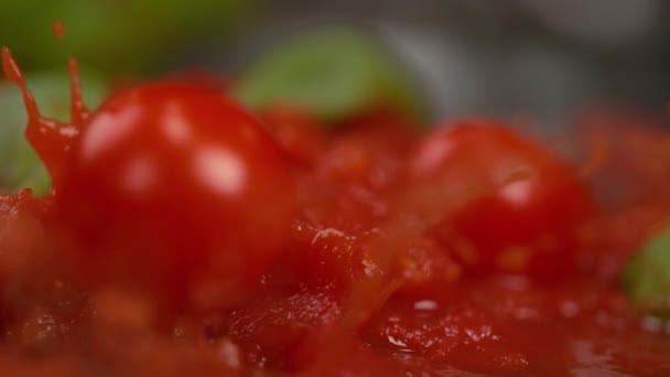 Makro: Leckere Tomatensauce mit Basilikumspritzern, wenn Kirschtomaten hineinfallen. - Filmmaterial, Video