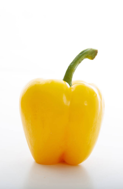 Campana gialla o peperone bulgaro con gambo isolato su fondo bianco. Ritratto verticale del vegetale integro, sano, dietetico. Cibo adeguato per vegani, vegetariani
. - Foto, immagini