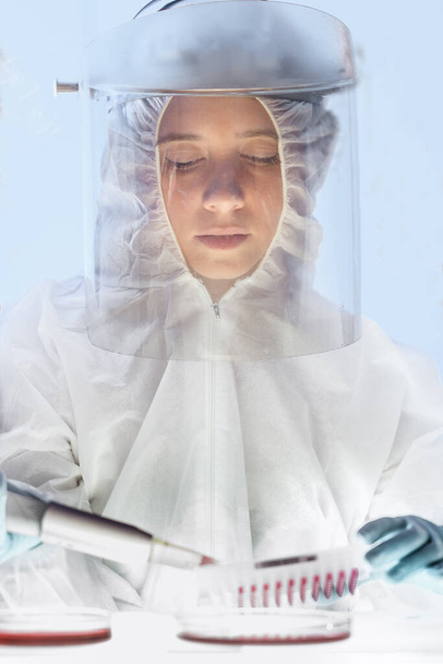 Γυναίκα επιστήμονας που εργάζεται στο εργαστήριο ανάπτυξης εμβολίων κατά του ιού του στέμματος του στέμματος με τον υψηλότερο βαθμό προστατευτικού εργαλείου. - Φωτογραφία, εικόνα
