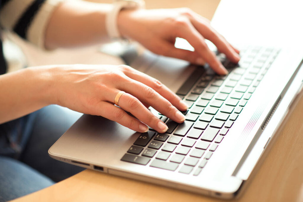 Женщина вручную набирает на ноутбуке клавиатуру дома, работает из дома, интернет вещей концепции. Карантин, изоляция и работа вне дома во время пандемии коронавируса
. - Фото, изображение