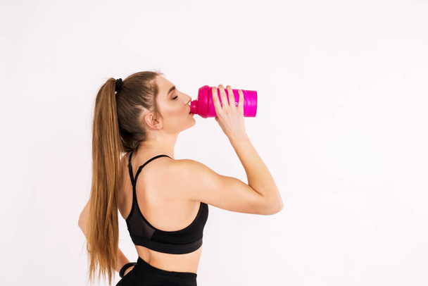 Fitness vrouw close-up met een waterfles op een witte achtergrond. Ruimte voor tekst - Foto, afbeelding