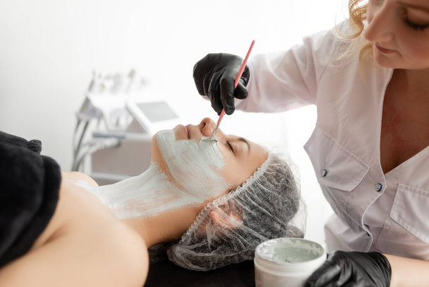 woman at a beautician appointment. applying a mask to the face. Anke treatment. It has a powerful anti-inflammatory and antibacterial effect. - Photo, Image