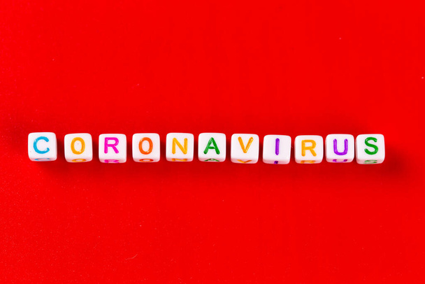 Pandémia és vírus koncepció - Coronavirus szó készült színes blokkok. Coronavirus szöveg piros háttérrel. Coronavirus koncepció felülnézet. - Fotó, kép
