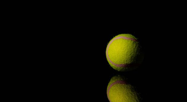 Bright Yellow Tennis Ball on dark mirror with reflections on a black background - Photo, Image