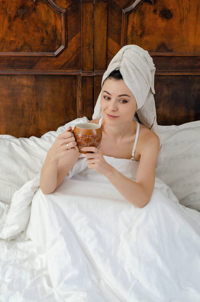 Donna dopo la doccia con un asciugamano in testa e una tazza di caffè in mano
. - Foto, immagini