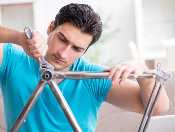 Nuori mies korjaamassa polkupyörää kotona - Valokuva, kuva