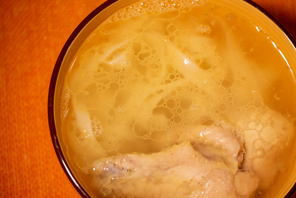 Kip poedelsoep. Kip en noodle soep op een oranje tafelkleed in een oranje bord. Voedselfotografie. Hete schotel. Aftreksel met noedels. Kip, noedels. - Foto, afbeelding