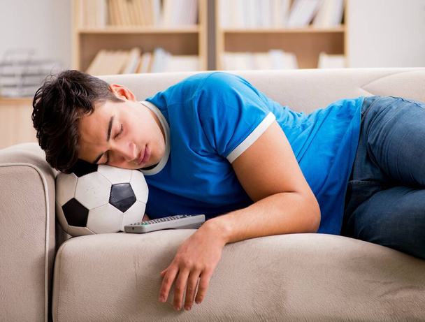 Чоловік дивиться футбол вдома, сидячи в дивані
 - Фото, зображення