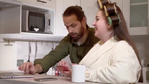 Married couple arguing in the kitchen looking at a laptop - Кадри, відео