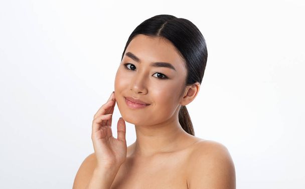 Attractive Asian Woman Touching Face Posing On White Studio Background - Photo, Image
