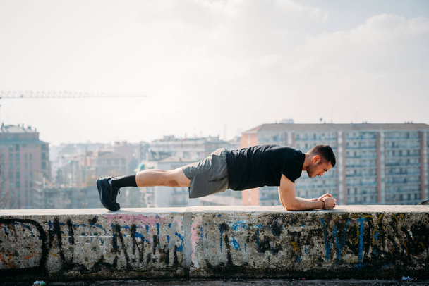 Young athletic man putdoor training doing plank position - concentration, sport, exercise concept - Photo, Image