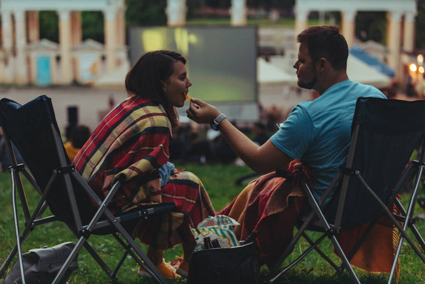 pár sedí v táboře-židle v městském parku hledá film venku na open air kino životní styl - Fotografie, Obrázek