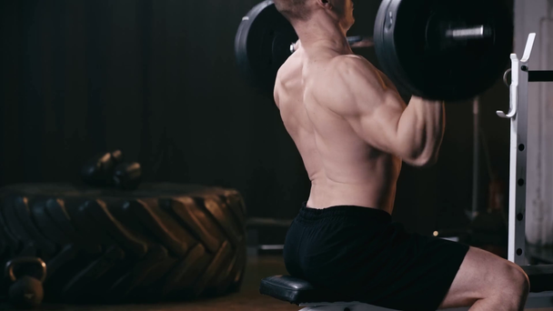 bijgesneden weergave van shirtloze man gewichtheffen lange halter in de sportschool  - Video