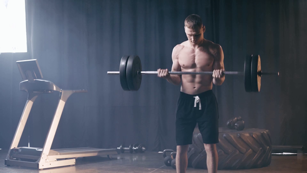 Uomo muscolare che si allena con il bilanciere in palestra  - Filmati, video