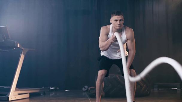 Zeitlupe eines athletischen Mannes, der mit Kampfseilen trainiert - Filmmaterial, Video