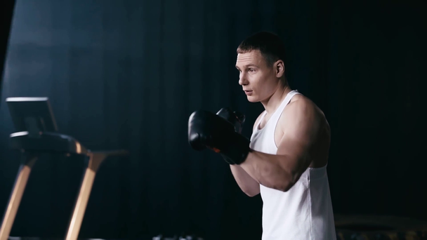 Lento movimiento del hombre en guantes de boxeo haciendo ejercicio cerca del saco de boxeo
  - Metraje, vídeo