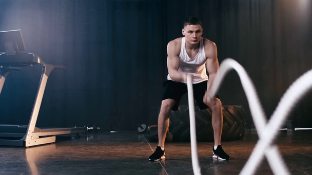 sportive man exercising with battle ropes in gym  - Video