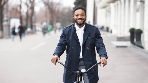 Handsome afro businessman riding his bike in city - 写真・画像