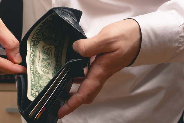 hombre muestra una billetera con un dólar en una camisa blanca en la oficina
 - Foto, imagen