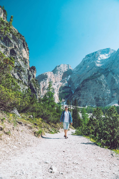 Sırt çantalı genç adam güneşli yaz etkinliklerinde dağlarda yürüyor. - Fotoğraf, Görsel