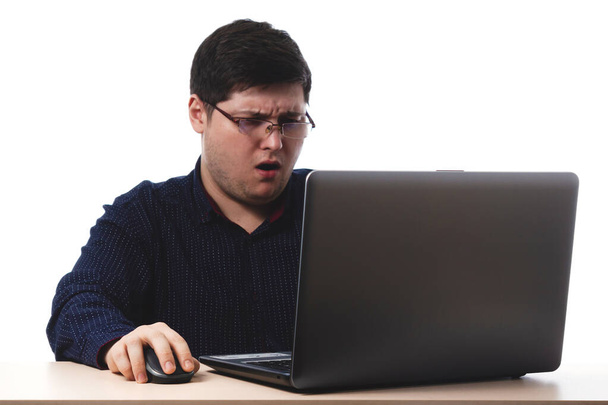 Giovane ragazzo con una camicia blu scuro dietro un computer portatile in occhiali per ufficio, visione d'affari su uno sfondo bianco. isolarsi. copia spazio
 - Foto, immagini