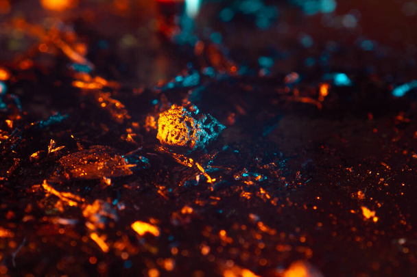 coals scatter in different directions with a blue-orange backlight on a dark background. close up copy space - Photo, Image