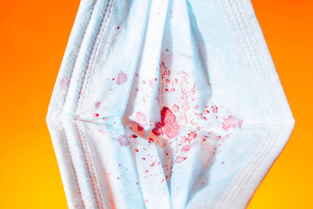オレンジの背景に乾燥血液中の医療ガーゼマスク。コピースペースを閉じて - 写真・画像