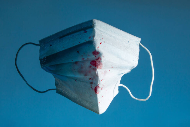 máscara de gasa médica azul con sangre en un espacio de copia de fondo azul. de cerca
 - Foto, imagen