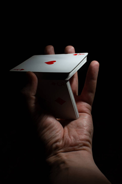 χέρι κρατήσει μια τράπουλα ένα χέρι ανακατέψτε volt πόκερ σε ένα μαύρο χώρο αντίγραφο φόντο. Κλείσιμο - Φωτογραφία, εικόνα