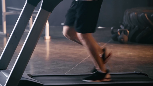 oříznutý pohled na atletického muže běžícího na běžícím pásu v tělocvičně  - Záběry, video