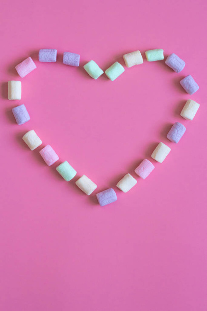 Text Happy and heart shape made by colorful marshmallows on pink background, macro. Fluffy marshmallows texture close up in pastel colors valentine day concept - 写真・画像