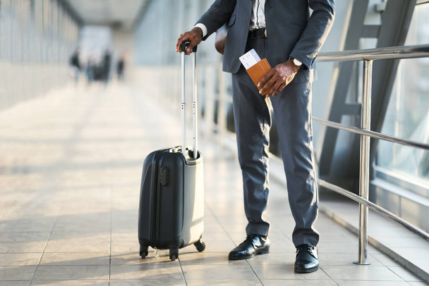 Неузнаваемый предприниматель с паспортом и авиабилетами, стоящими в аэропорту
 - Фото, изображение
