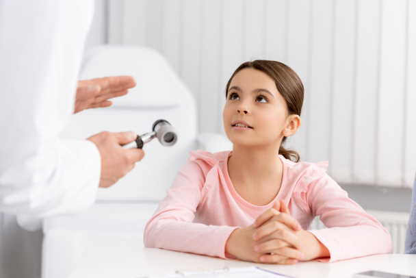 περικοπή άποψη του ent γιατρό δείχνει ωτοσκόπιο σε χαριτωμένο προσεγμένο παιδί - Φωτογραφία, εικόνα