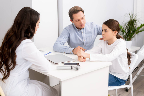 padre attento seduto vicino a figlia preoccupata durante la consultazione con il medico ent
 - Foto, immagini