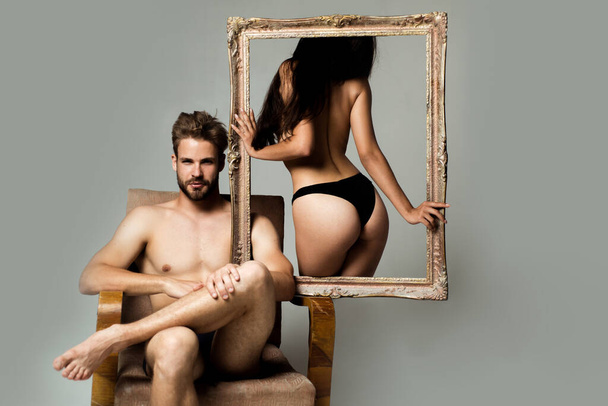 Portrait of a young woman holding a frame. Couple. Sensual woman with perfect body in black lingerie standing near muscular man. Pose for family portrait. Valentines day. Romantic and love. - Foto, Bild