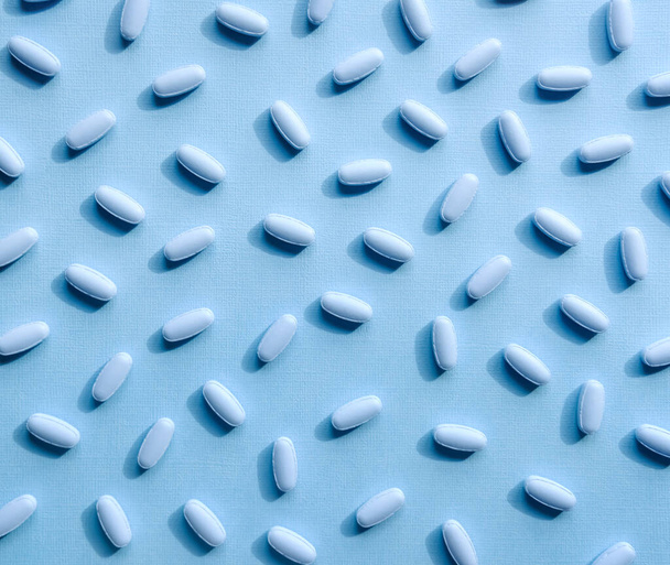 Niebieskie tabletki i kapsułki na pastelowym tle. - Zdjęcie, obraz