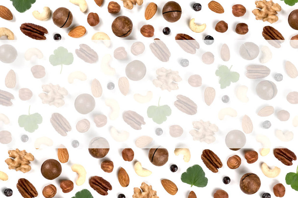 A pattern of nuts on a white background, decorated with green leaves. View to the top, there is a place for inscription. - Foto, imagen