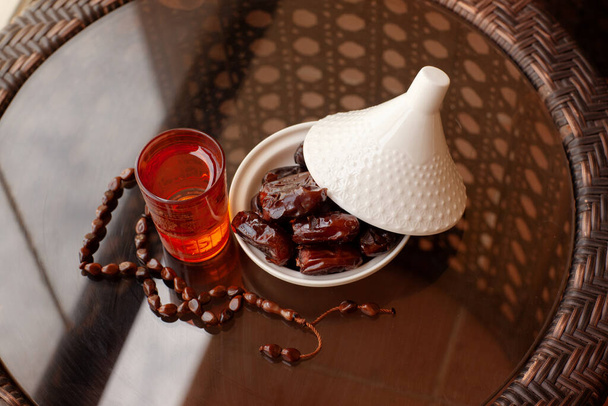 Date in un piatto di vetro con un coperchio, una bevanda orientale e un rosario su un tavolo di vetro. Il mese santo islamico del Ramadan. Biglietto d'auguri
 - Foto, immagini
