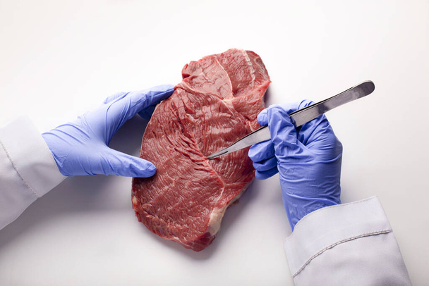 Вчений в рукавичках здійснює контроль якості м'яса
 - Фото, зображення