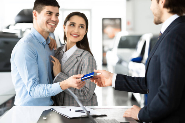 Paar Kopen Auto geven Credit Card aan de verkoper - Foto, afbeelding