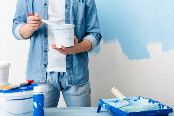 Homemade repairs concept. Guy mixes paint in bucket - 写真・画像