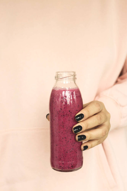 Berry smoothie in a bottle. Healthy breakfast in the hands of a woman. - 写真・画像