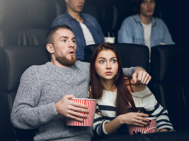 Young scared couple watching thriller in cinema - Φωτογραφία, εικόνα